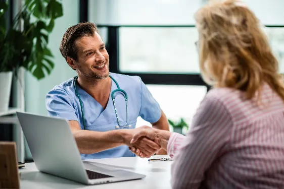 happy doctor shaking hands with wife his senior patient medical clinic