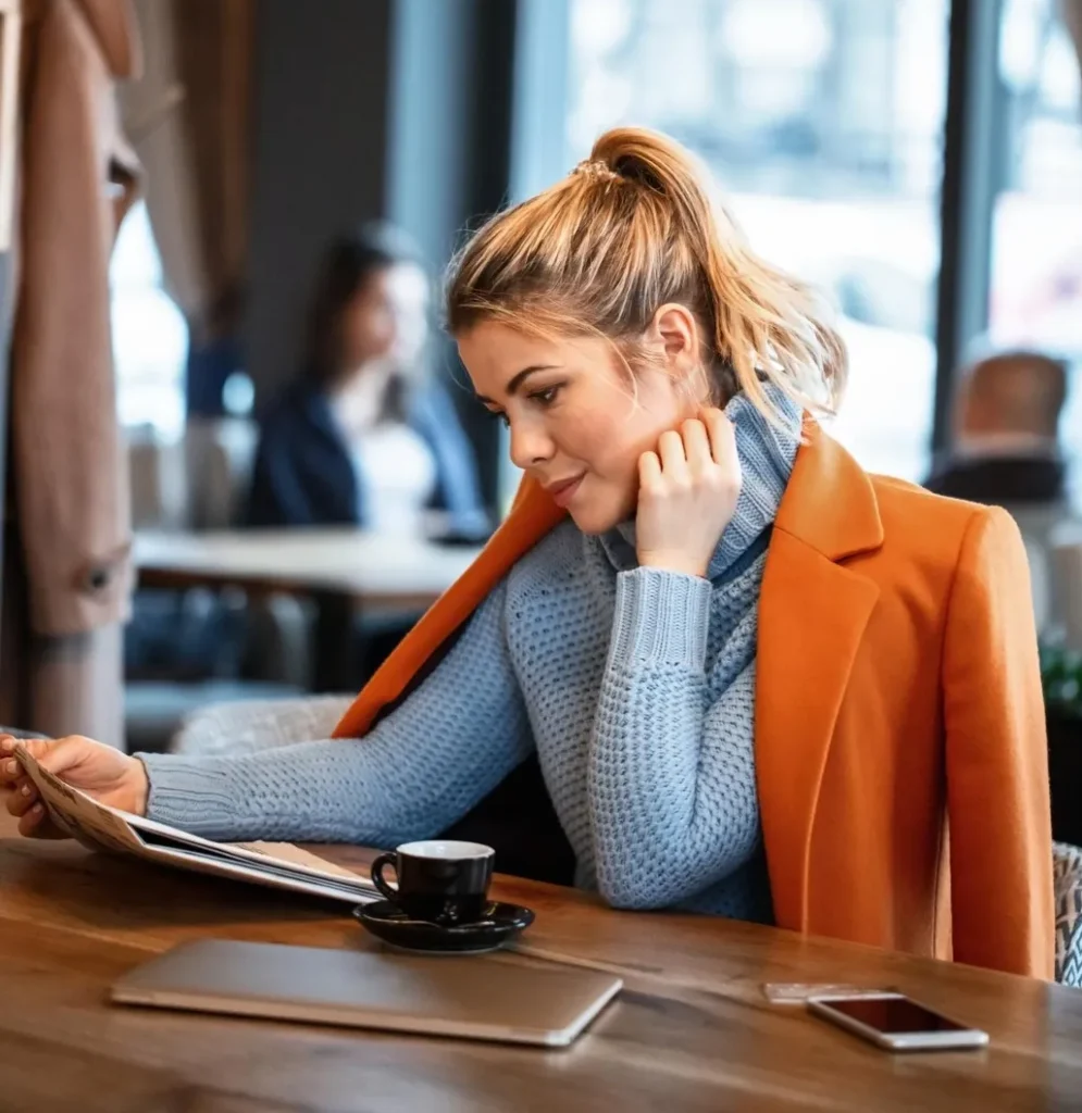 young female entrepreneur relaxing coffee break reading daily newspaper cafeteria@3x e1713538520786